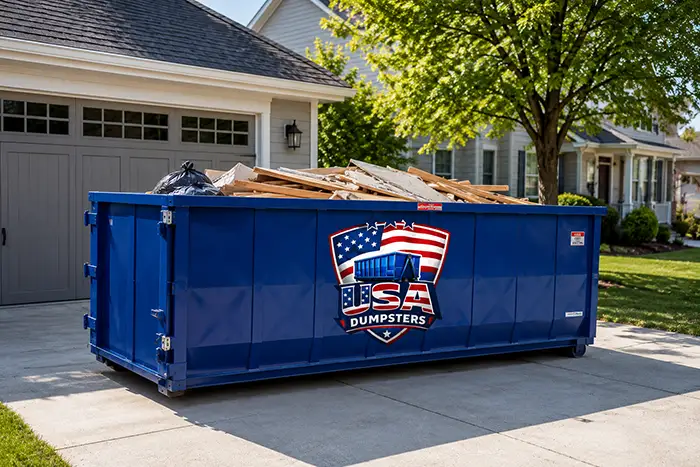 residential grey blue house with blue dumpster with company logo